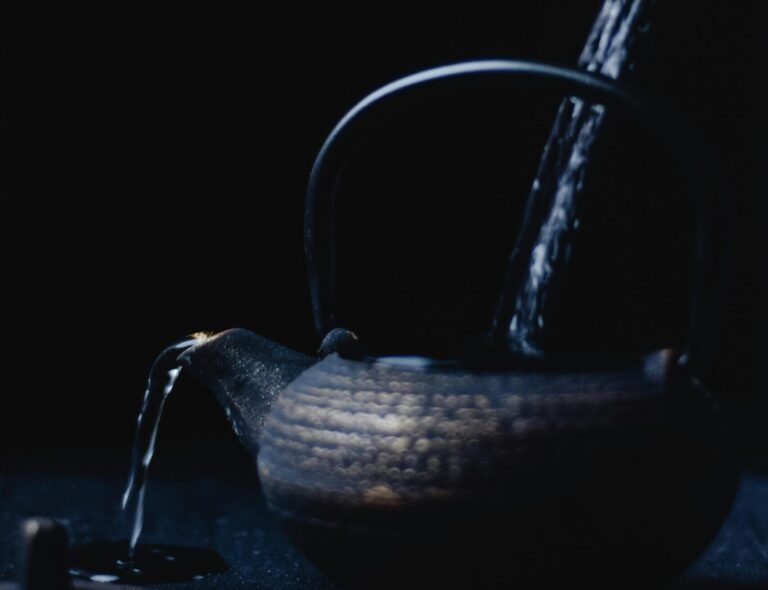 A cast iron kettle being filled as part of a slow brewing process, with steam rising and liquid gently overflowing from the spout, symbolising ideas steeping into clarity and marketing resources being brewed for deeper impact without added strain.