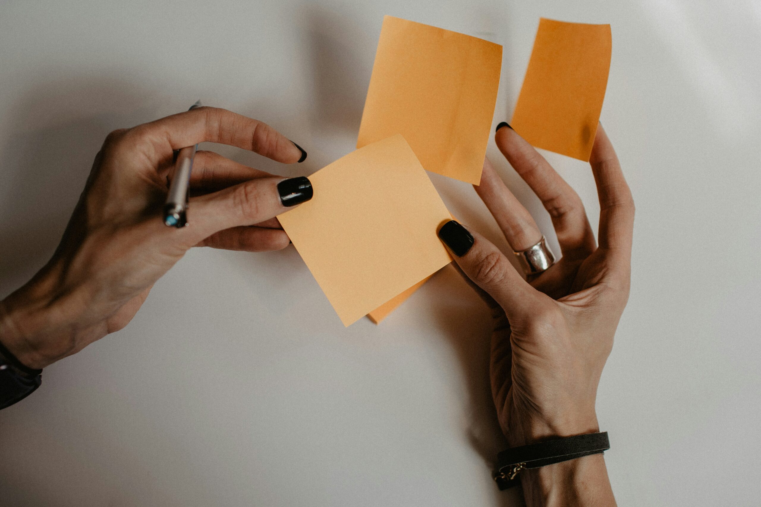 Hands holding multiple notes representing fragmented interpretations of audience needs before they are refined into insight.